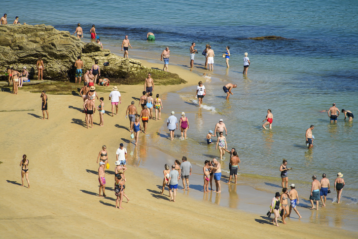 Personas refrescándose del calor este lunes en el Pico del Loro donostiarra, entre La Concha y Ondarreta. (Jon URBE | FOKU)