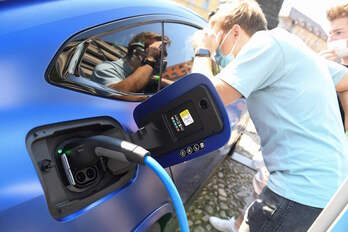 Una persona mira al interior de un vehículo eléctrico en plena carga, en la Feria del Motor de Múnich, el pasado jueves. (Tobias SCHWARZ/AFP)