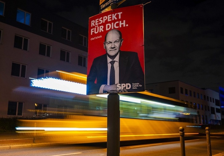 Un autobús pasa raudo junto a un cartel electoral de Scholz. (John MACDOUGALL/AFP)
