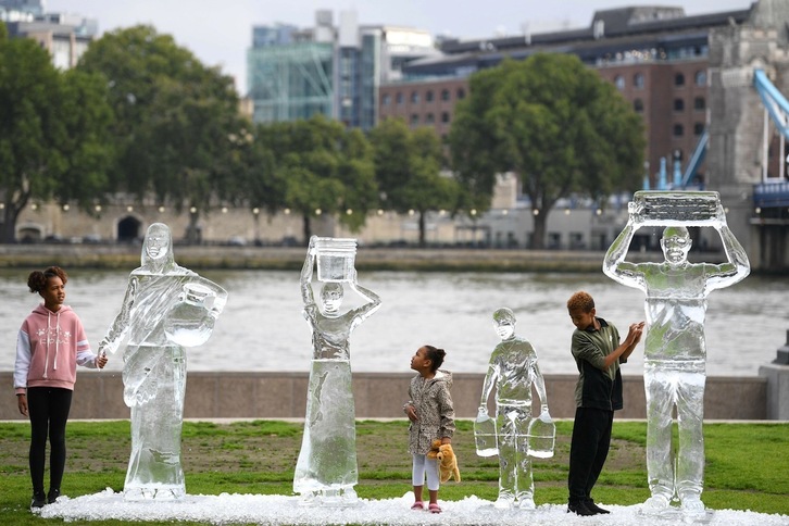 Niñas y niños observan unas esculturas de hielo que representan a personas transportando agua. Fue una acción de Water Aid para mostrar la amenaza del cambio climático realizada el 15 de setiembre en Londres. (Daniel LEAL-OLIVAS/AFP)