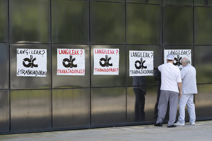 Dos trabajadores colocan carteles de protesta en la fachada de Onkologikoa. (Gorka RUBIO/FOKU)