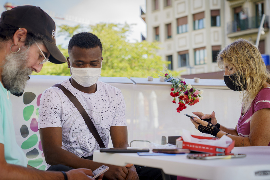 Bolondresak, migrante batek mugikorrean dituen arazoak konpontzeko laguntzen. (Gorka RUBIO | FOKU)