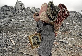 Una mujer carga con el retrato de su marido y dos mantas en Chechenia en 2000. (Éric BOUVET)