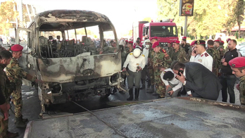 Labores de retirada del autobús militar calcinado. (AFP)