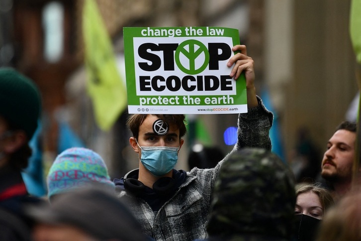 Un activista climático muestra un cartel con el lema ‘Stop al ecocidio’ durante la manifestación que ha tenido lugar en Glasgow este miércoles. (Ben STANSALL/AFP)