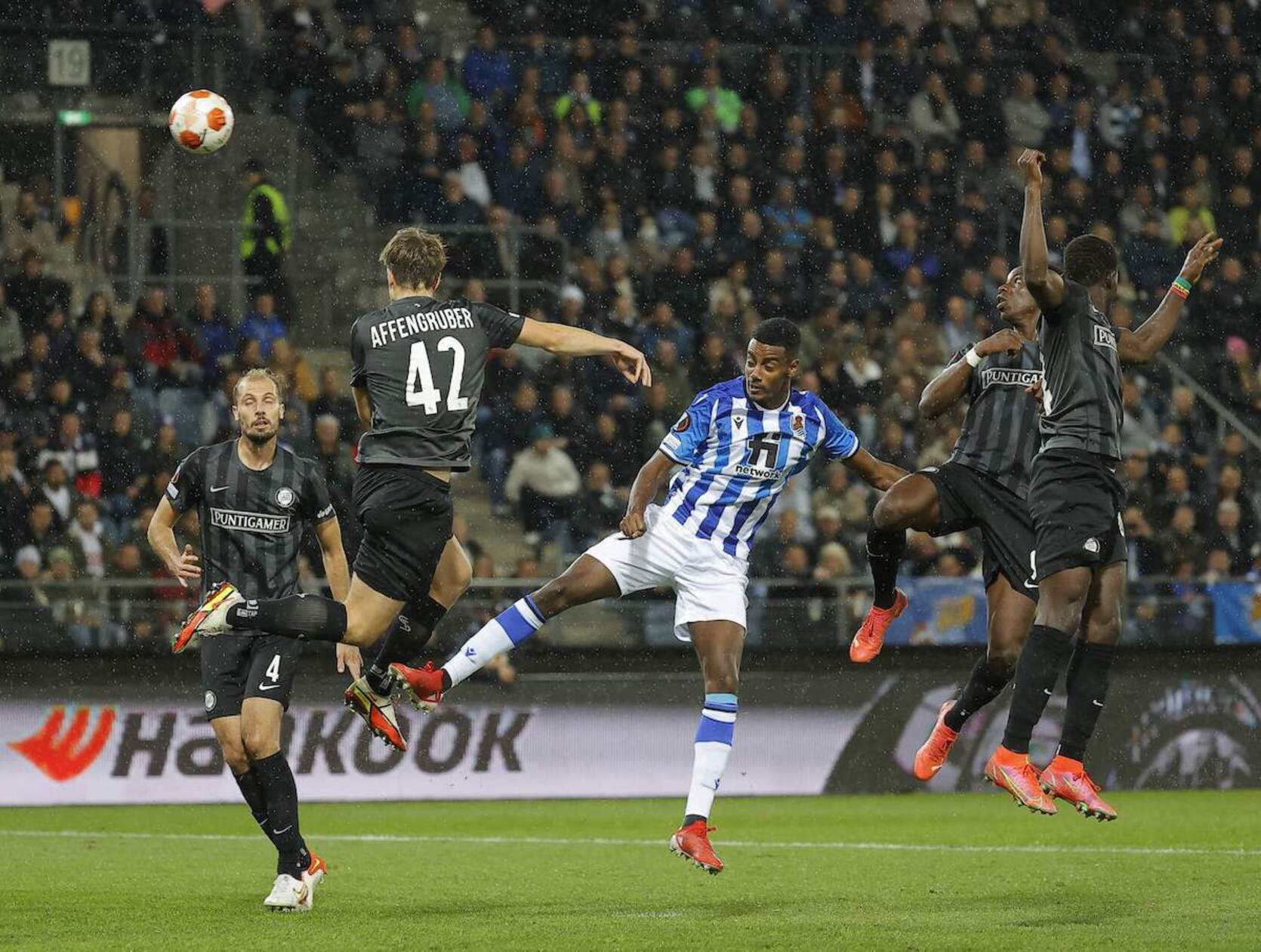 Los jugadores del Sturm Graz pugnan el balón ante el delantero txuri-urdin Isak en la tercera jornada de la fase de grupos de la Europa League. (Erwin SCHERIAU / AFP)