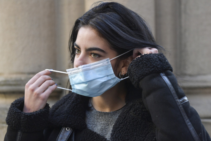 Una joven se coloca una mascarilla en exterior. (Idoia ZABALETA/FOKU)
