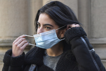 Una joven se coloca una mascarilla en exterior. (Idoia ZABALETA/FOKU)