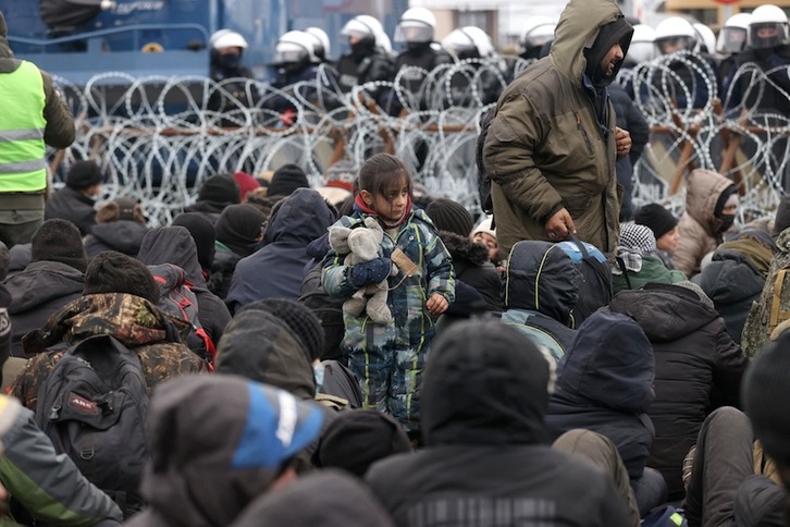 Refugiados se agolpan en la frontera frente a los policías polacos. (OKSANA MANCHUK-AFP)