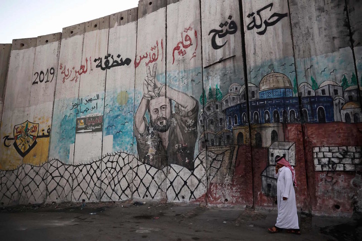 Un hombre camina junto al muro del aparthei en Al-Azariyeh, en la Cisjordania ocupada. (Hazem BADER/AFP)