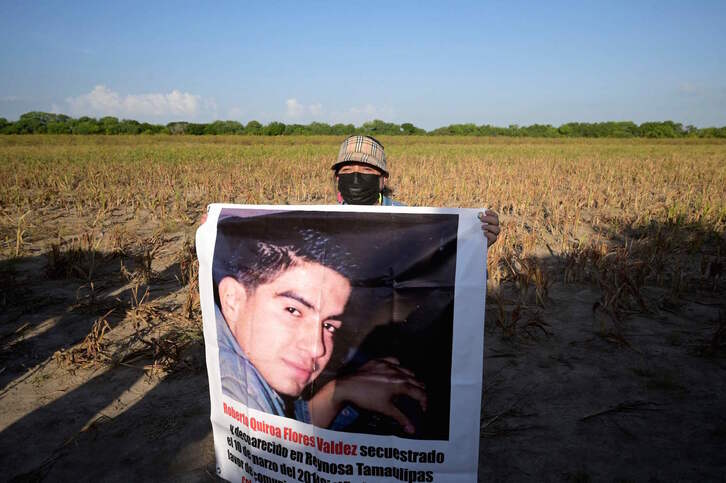 Una mujer sostiene la imagen de su hijo desaparecido, en la búsqueda en «La Bartolina». (Alfredo ESTRELLA | AFP)
