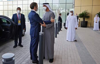 Efusivo saludo entre Macron y Mohammed bin Zayed al-Nahyan a la entrada de la Expo de Dubai. (Thomas SAMSON/AFP)