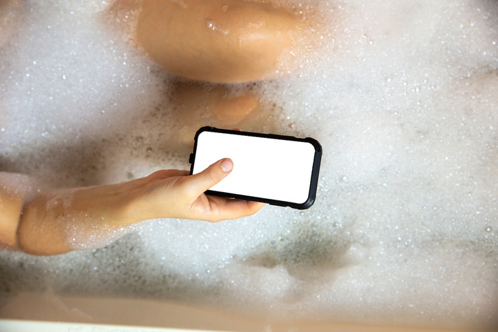 Una mujer usa su teléfono móvil en la bañera. (GETTY)