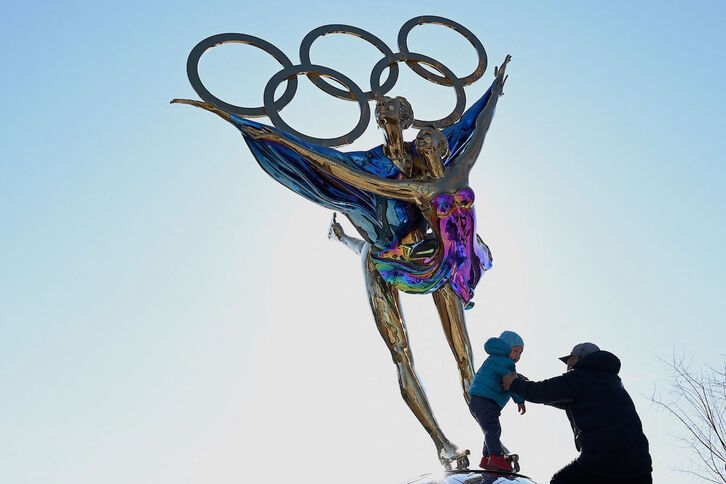 Un niño juega junto a una escultura con los arcos olímpicos en Pekín. (Noel CELIS/AFP)