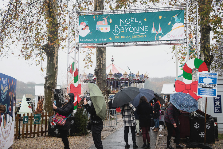 Vecinos de Baiona difrutan, bajo la lluvia y en un clima de creciente preocupación sanitaria, del Mercado de Navidad instalado en las cercanías del Ayuntamiento. (Guillaume FAUVEAU)