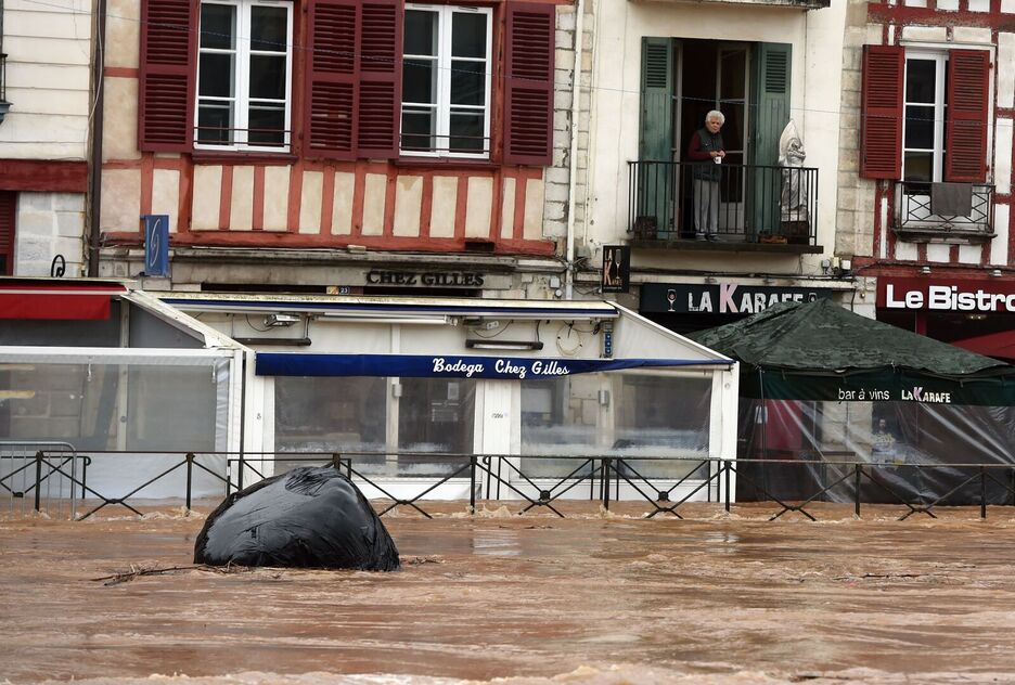 Una persona mira desde el balcón la calle inundada en Baiona. (Gaizka IROZ/AFP)