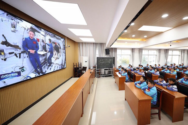 Escolares chinos atienden desde su escuela em Danzhai una clase on line con astronautas de la estación espacial de Tiangong. (STR | AFP)