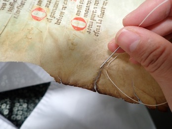 Costura para reparar un desgarro en uno de los documentos municipales restaurados por el Archivo General de Nafarroa.