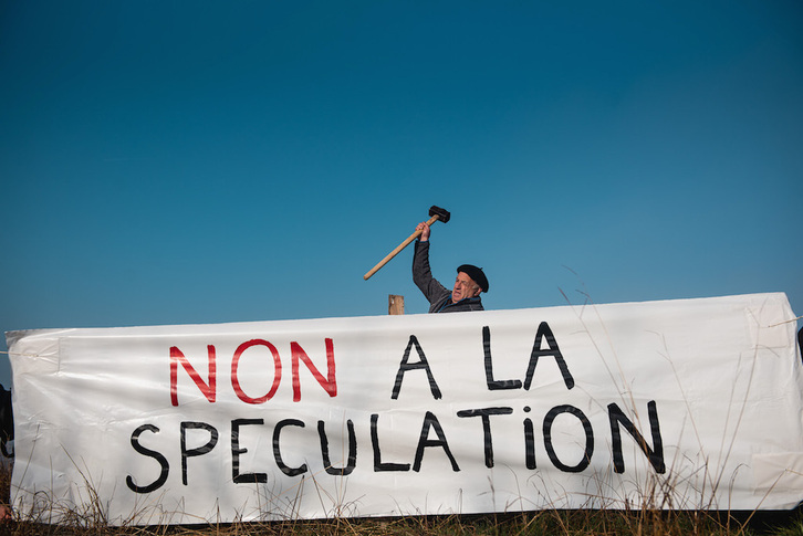Aiherrako herritar bat espekulazioa salatzeko banderola finkatze lanetan.
