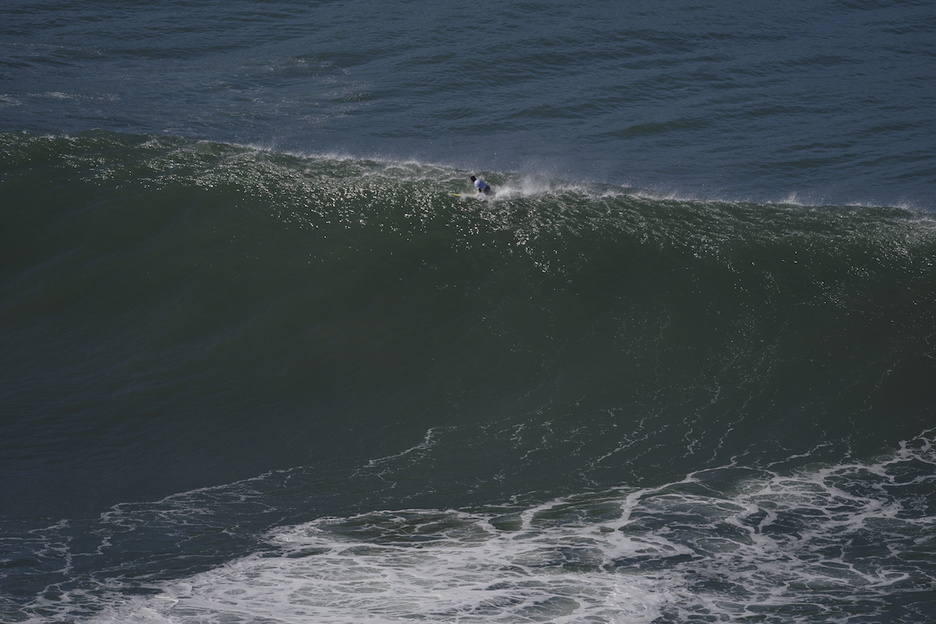 Surflari bat, olatuaren goi-goian.