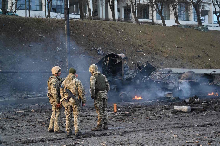 Soldados ucranianos contemplan un vehículo destruido en Kiev. 
