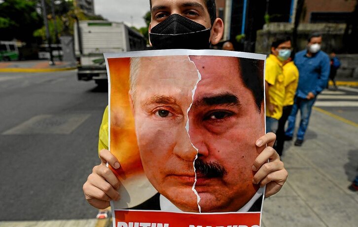 Un opositor denuncia la invasión de Ucrania equiparando los rostros de Putin y Maduro. (Federico PARRA/AFP)