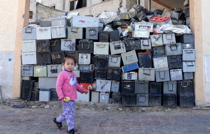Una joven palestina camina por delante de un muro de estas baterías.