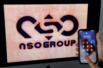Un teléfono móvil junto al logo del grupo NSO, desarrollador del software de espionaje Pegasus.