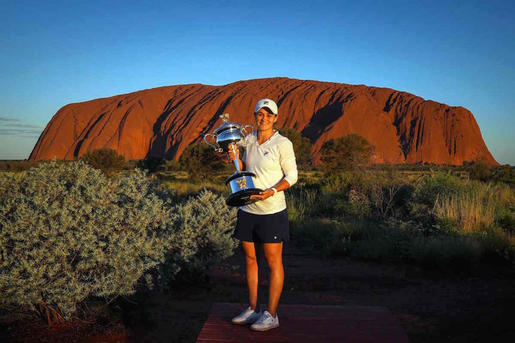 Ashleigh Barty posa ante el icónico monte Uluru con el trofeo ganado en el Open de Australia.