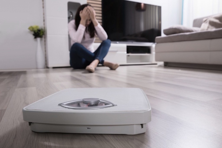 Anorexia duen pertsona bat pisu baten aurrean.