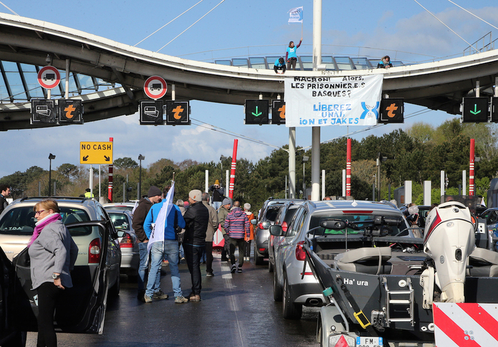 Activistas colocan una pancarta en el tejado del peaje de la A63 en Biarritz, cerrado durante la acción de Bake Bidea y Artesanos de la Paz.