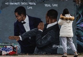 Una mujer fotografía un mural del artista callejero Eme Freethinker, en Berlín, que muestra la imagen de Will Smith abofeteando a Chris Rock durante la ceremonia de los Oscar.