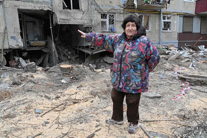 Una mujer ucraniana muestra los daños sufridos por un edificio en Jarkov.