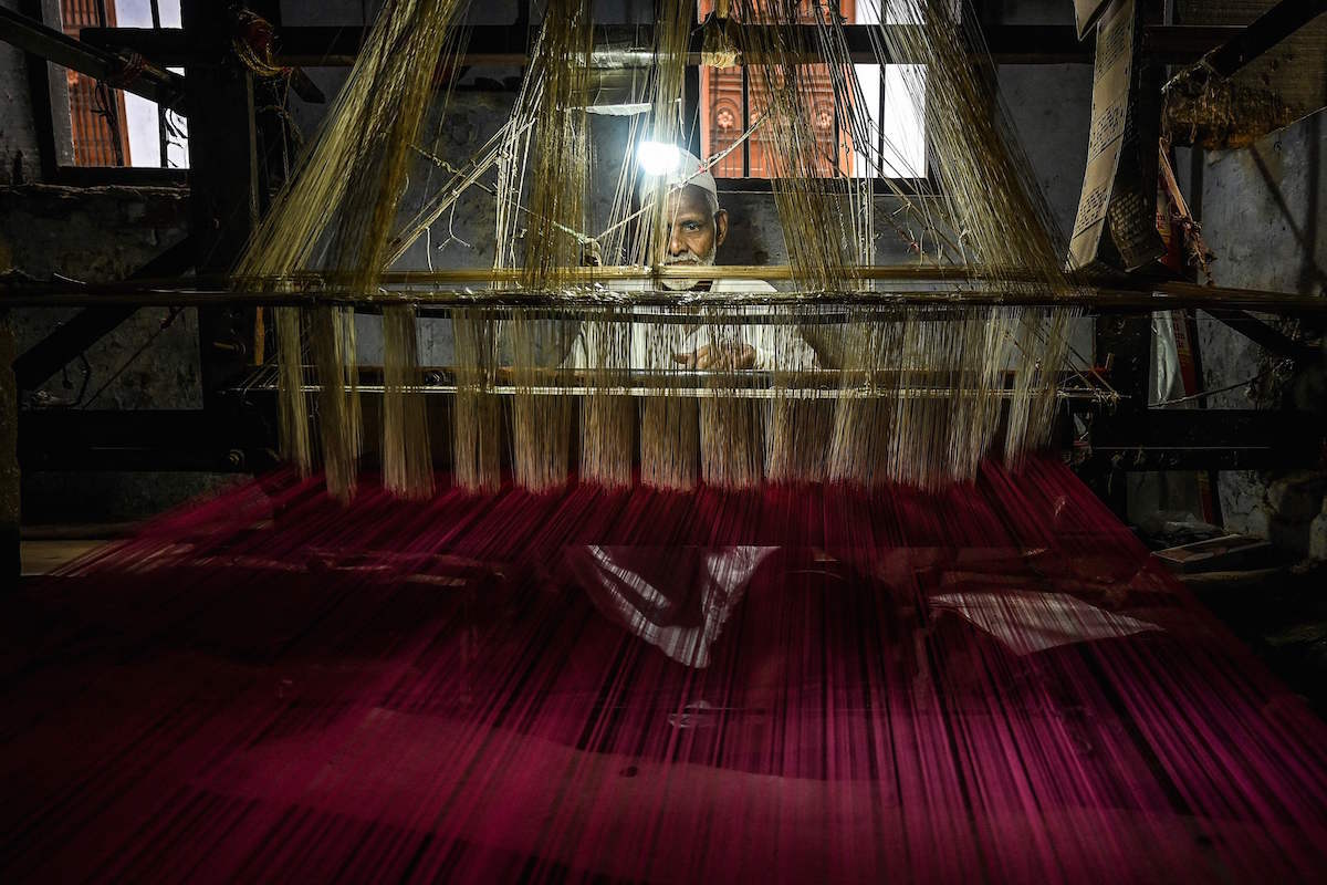 Un trabajador usa un telar manual para tejer un sari de seda en un taller en Varanasi. (Money SHARMA/AFP)