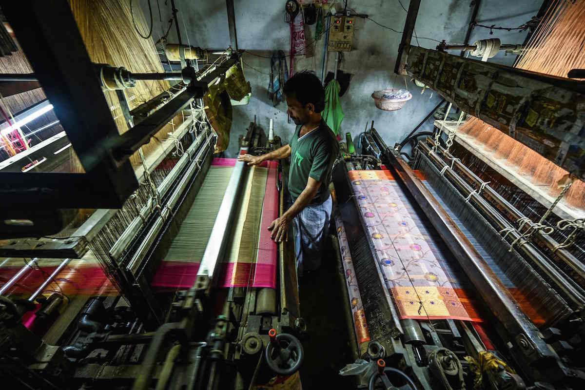 Un trabajador usa telares mec&aacute;nicos para tejer un sari de seda en un taller en Varanasi. (Money SHARMA/AFP)