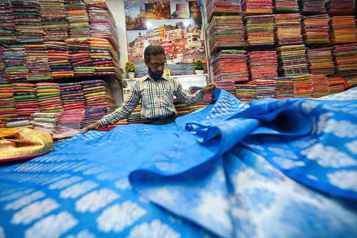 Un comerciante muestra un sari tradicional en una tienda en Varanasi. (Money SHARMA/AFP)