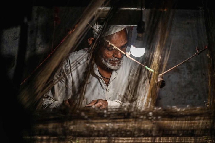 Un trabajador teje a mano un sari en la ciudad india Varanasi.