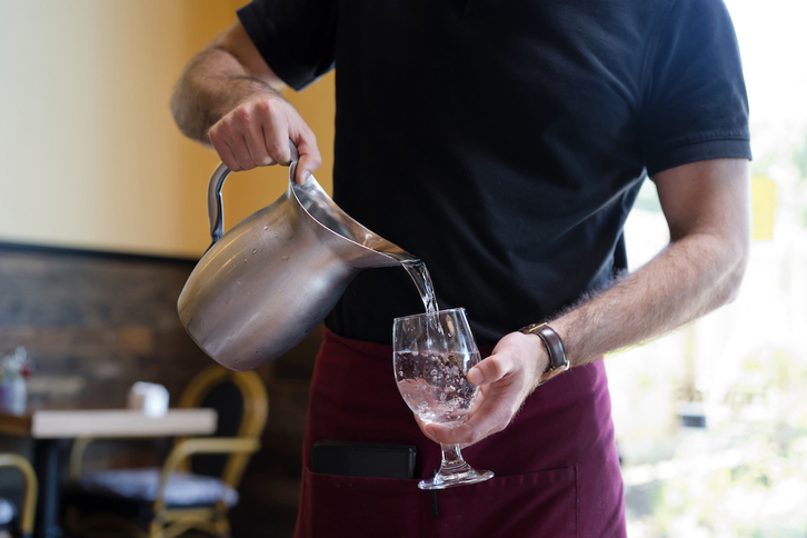 Un camarero sirve agua de una jarra.