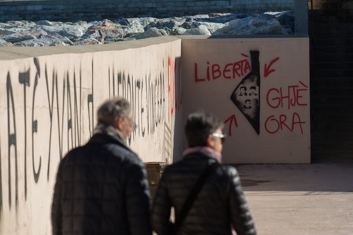 Una pareja pasa frente a varias pintadas en honor Yvan Colonna, el FLNC y los presos políticos de Corsica en el puerto de Bastia.
