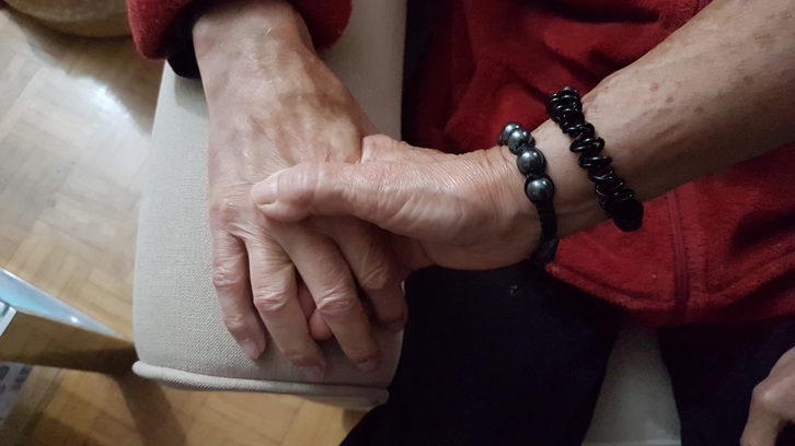 Una cuidadora toma la mano de su marido enfermo de Alzheimer.