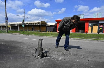 Un hombre mira los restos de un misil que impactó en una carretera en las afueras de Jarkov.