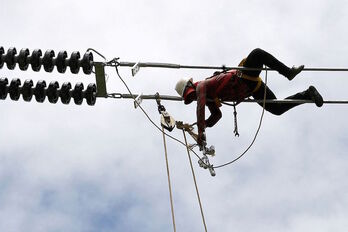 Un operario ajustando unos cables de alta tensión