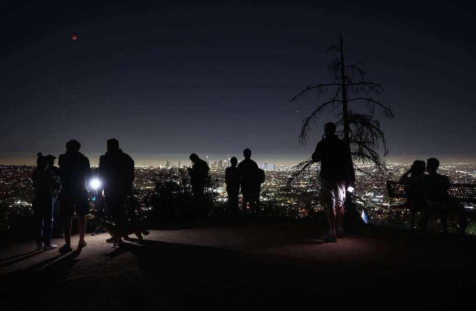 Aficionados contemplan el espectáculo desde el parque Griffin, en lo alto de Los Ángeles, en EEUU. 