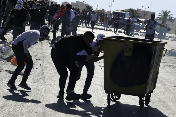 Manifestantes palestinos se protegen tras un contenedor en el 74º aniversario de Nakba.