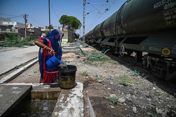 Una mujer llena un balde con agua suministrada por un tren especial en Pali, oeste de India.