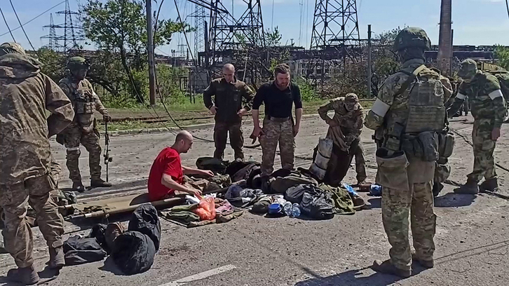 Imagen difundida por Moscú en la que se ven militares rusos vigilando a soldados ucranianos tras dejar Azovstal. 