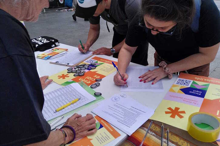 Una mujer firma para solicitar la regularización de las personas migradas que residen en el Estado español.