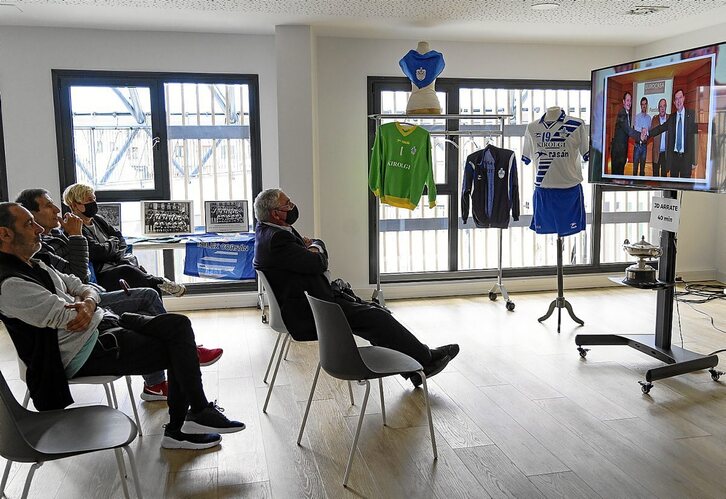 Bisitari batzuk Arrateko taldeei buruzko bideoa ikusten.