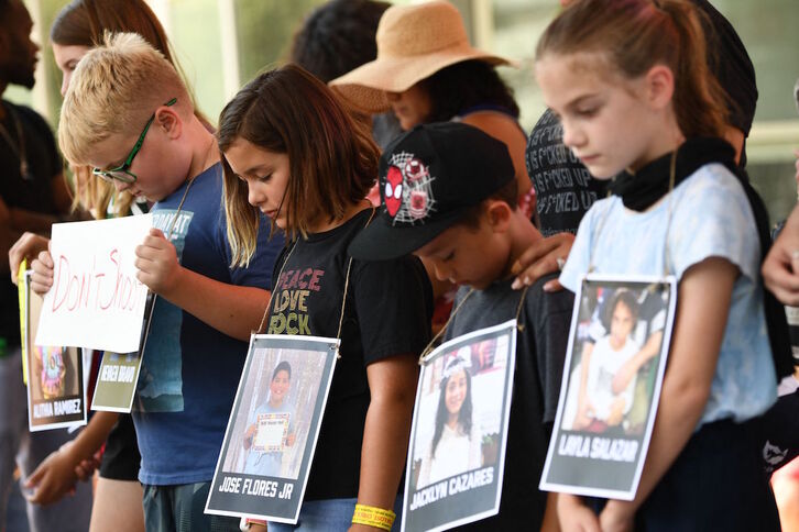 Varios niños con fotos de las víctimas de la masacre de Uvalde participan en el minuto de silencio frente al Centro de Convenciones George R. Brown, en Houston, donde la NRA celebra su reunión anual.