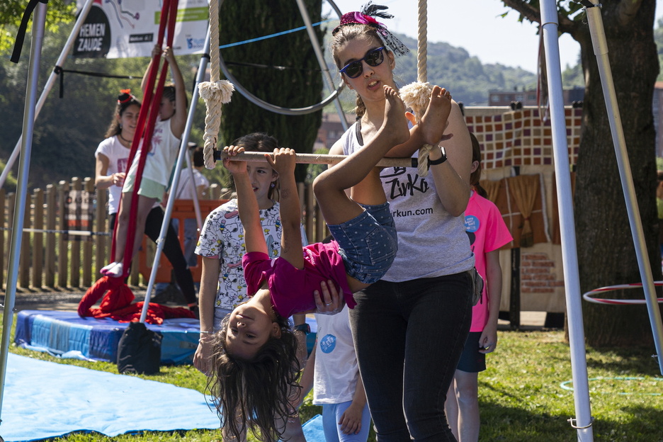 Trapezista lanetan haur bat, ingururako perspektiba aldatuta.